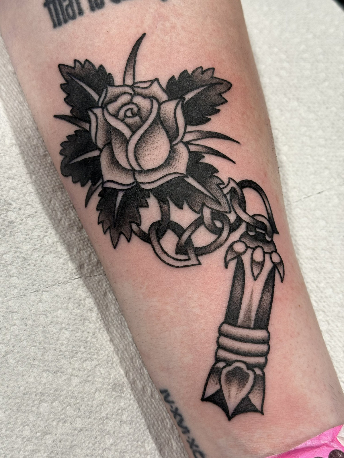 Black-and-gray rose dagger forearm tattoo by Kara at Last Hope Tattoo Company in Toledo